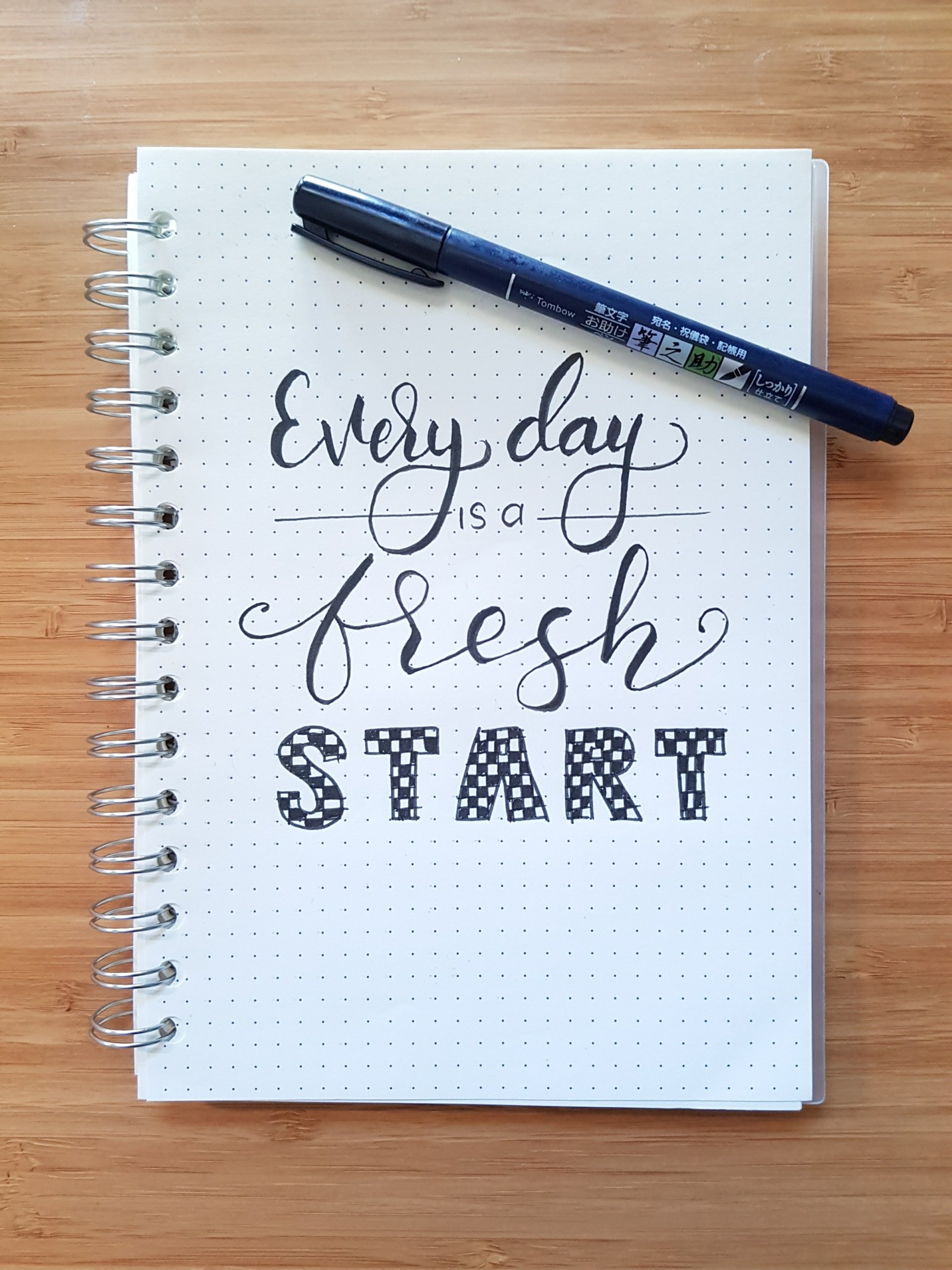 How mental - a spiral calligraphy notebook and a pen that reads Every day is a fresh start