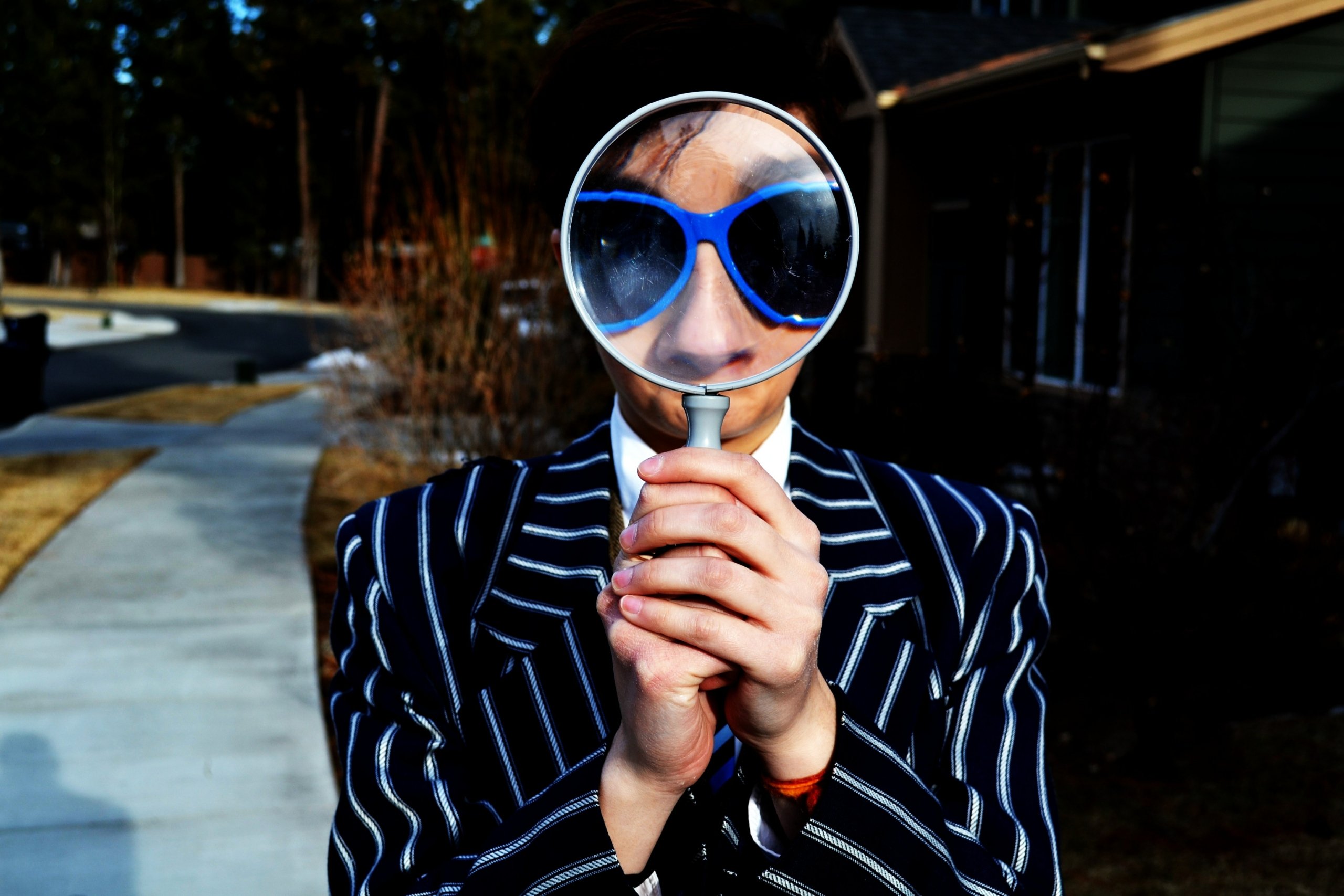 George Taktak, the interview with a person in a chalk-stripe suit using a magnifying glass
