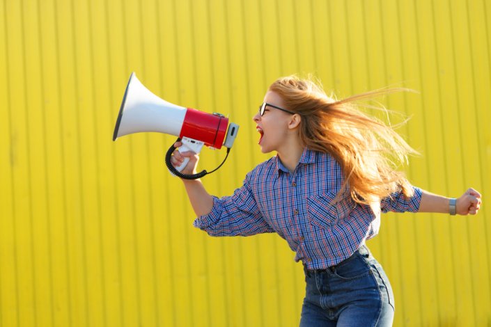 Young woman protesting against public sexual harassment yelling in megaphone