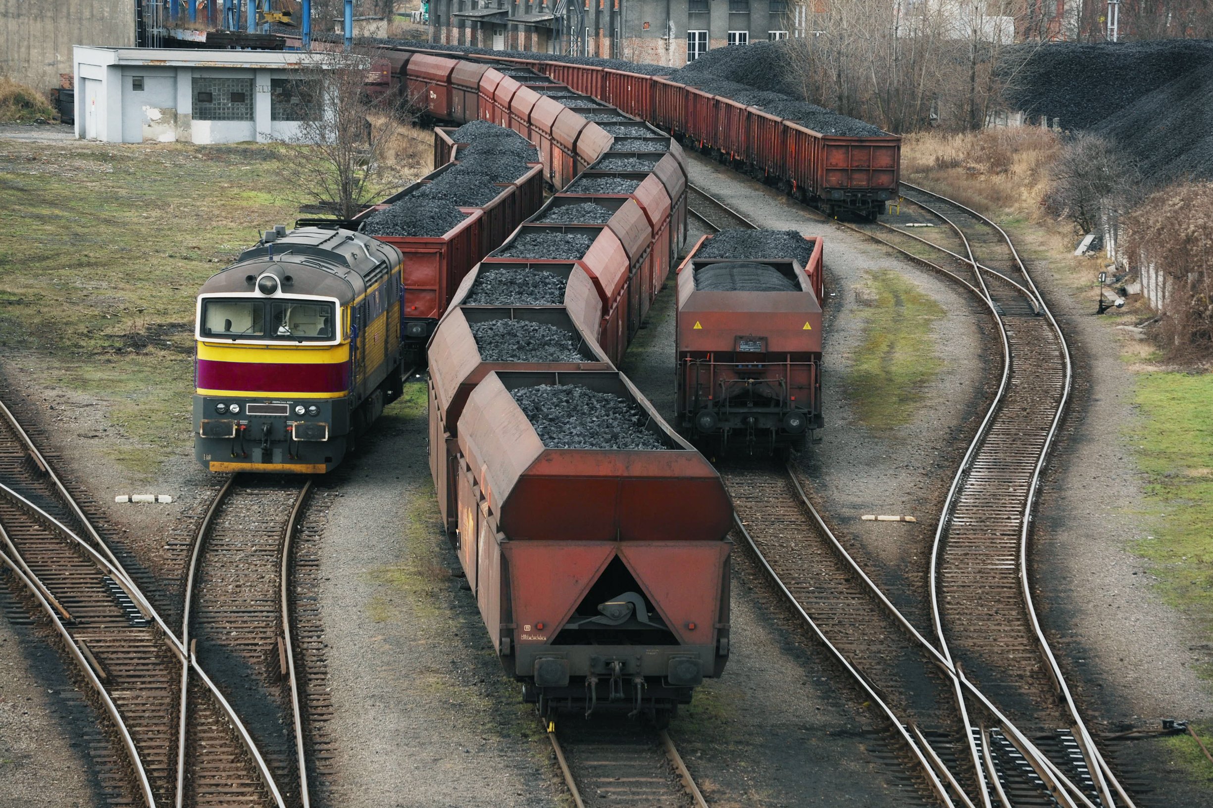 Cargo trains loaded with coal advance simultaneously on 4 separate, winding tracks destined for Coal power plants