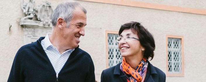 A light-haired man in a cardigan and a dark-haired woman wearing a colorful scarf - therapists Roland and Sabine Bosel - gaze smilingly at each other.